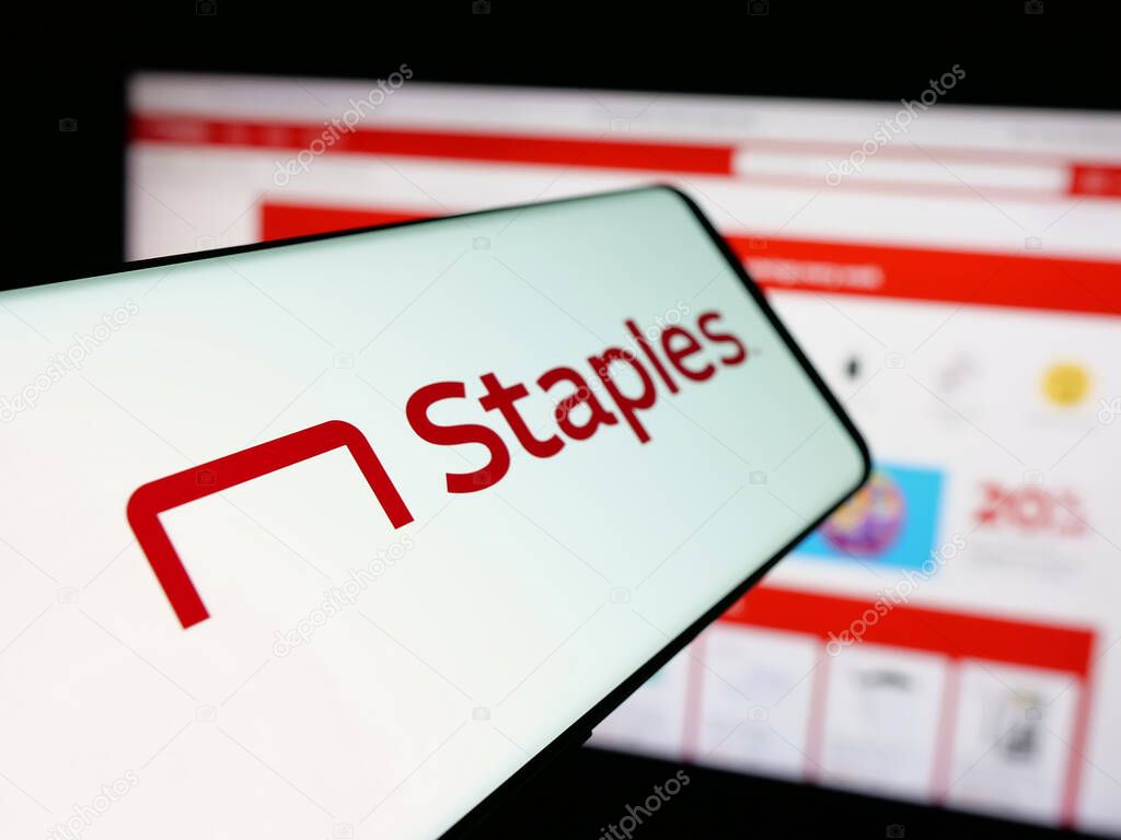 Stuttgart, Germany - 05-26-2025: Smartphone with logo of US office supply retail company Staples Inc. on screen in front of website. Focus on center-left of phone display.