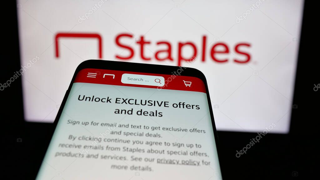 Stuttgart, Germany - 05-26-2025: Mobile phone with website of US office supply retail company Staples Inc. on screen in front of logo. Focus on top-left of phone display.