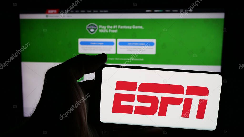 Stuttgart, Germany - 05-27-2025: Person holding mobile phone with logo of US cable sports television channel ESPN on screen in front of web page. Focus on phone display.