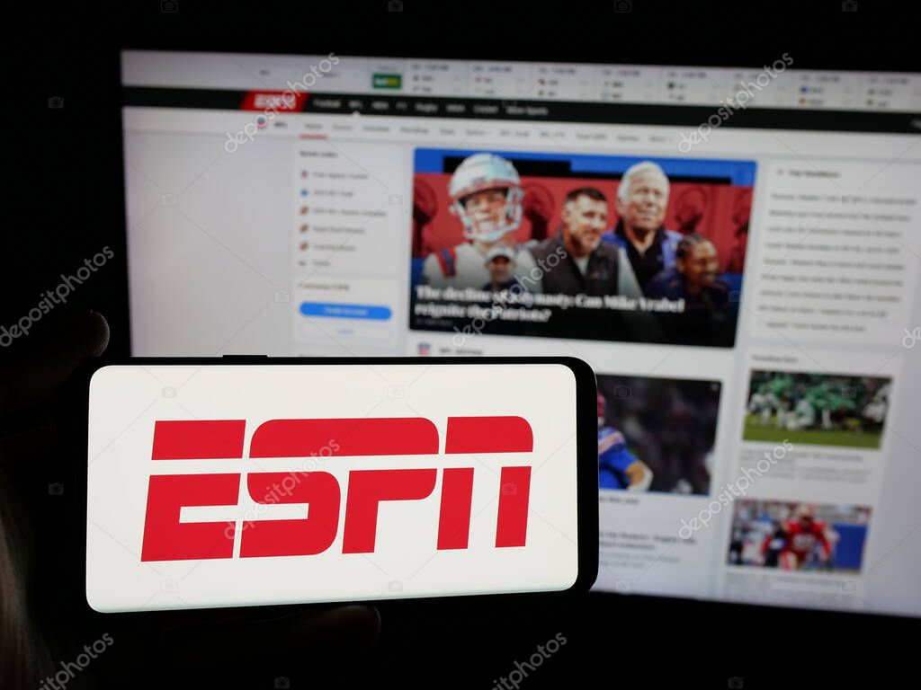 Stuttgart, Germany - 05-27-2025: Person holding smartphone with logo of US cable sports television channel ESPN on screen in front of website. Focus on phone display.