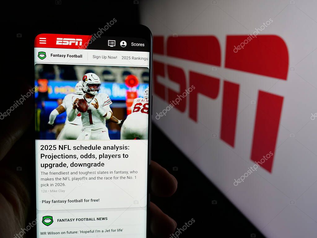 Stuttgart, Germany - 05-27-2025: Person holding smartphone with web page of US cable sports television channel ESPN on screen in front of logo. Focus on center of phone display.