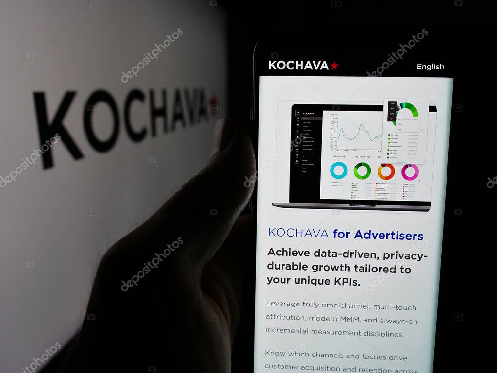 Stuttgart, Germany - 05-29-2025: Person holding smartphone with web page of US data solutions company Kochava Inc. on screen in front of logo. Focus on center of phone display.