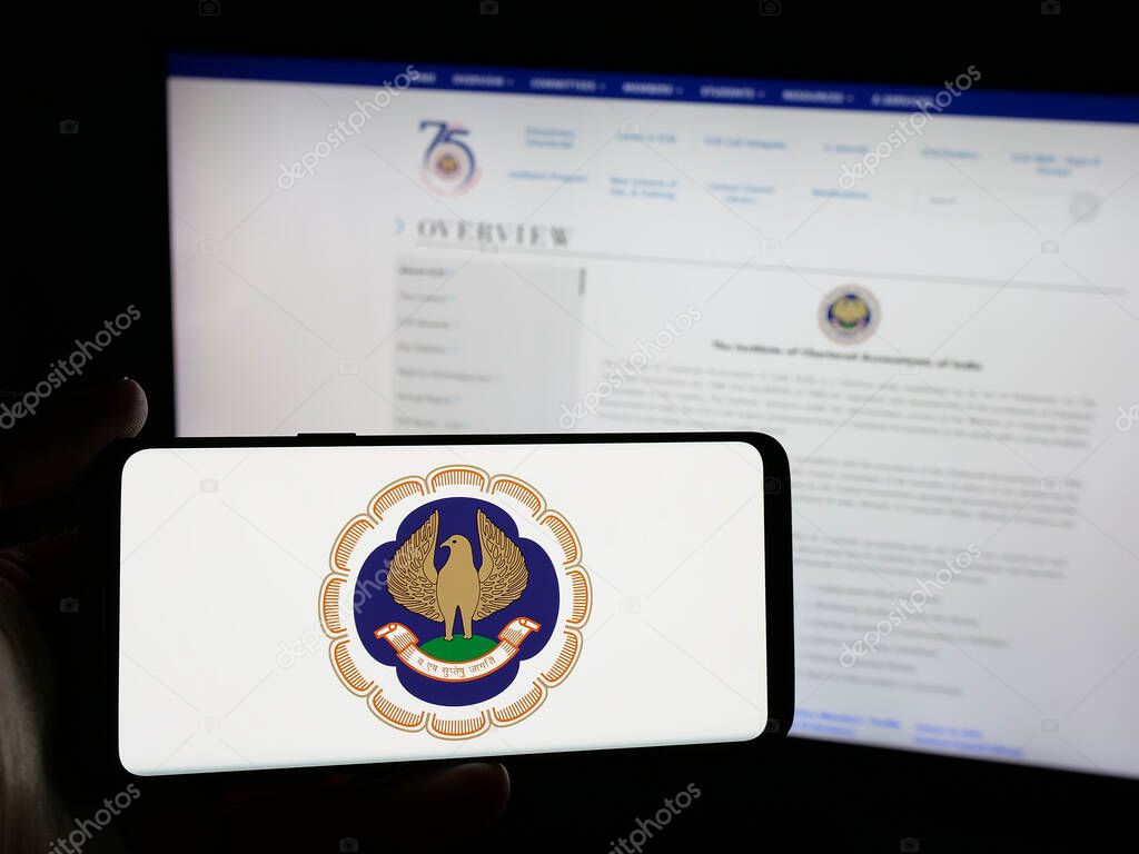 Stuttgart, Germany - 05-29-2025: Person holding smartphone with logo of Institute of Chartered Accountants (ICAI) on screen in front of website. Focus on phone display.