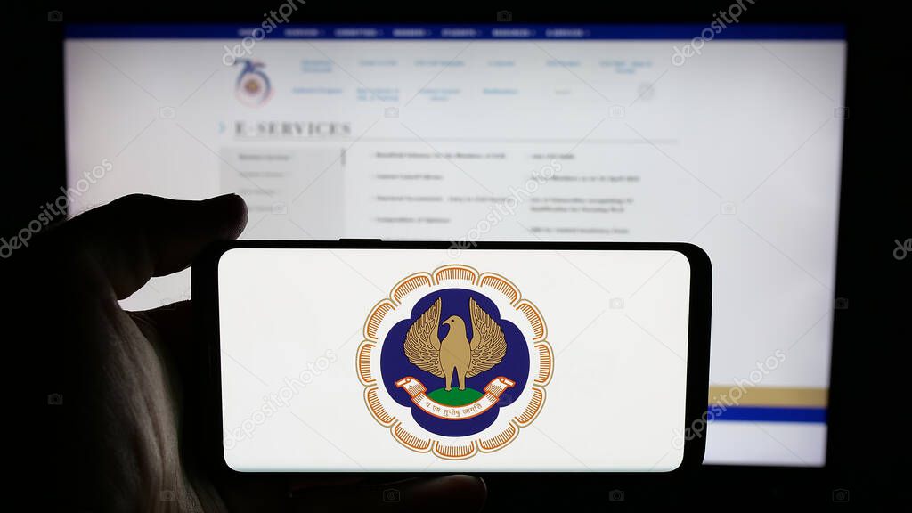 Stuttgart, Germany - 05-29-2025: Person holding cellphone with logo of Institute of Chartered Accountants (ICAI) on screen in front of webpage. Focus on phone display.