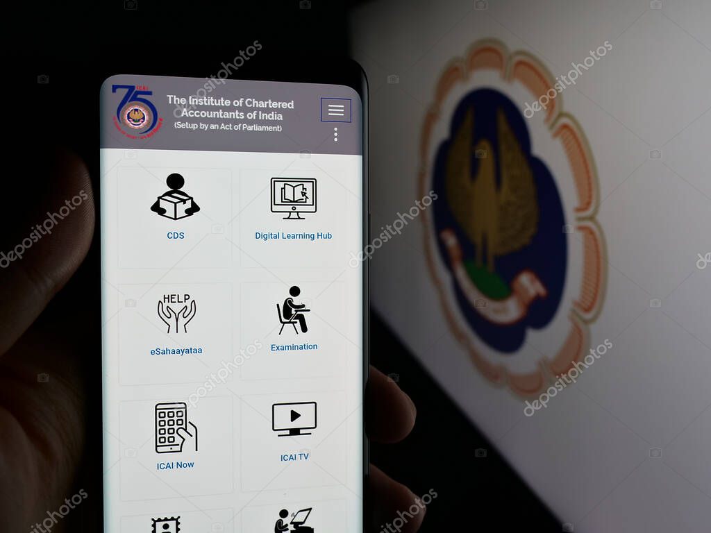 Stuttgart, Germany - 05-29-2025: Person holding smartphone with web page of Institute of Chartered Accountants (ICAI) on screen in front of logo. Focus on center of phone display.