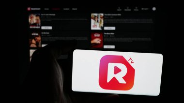 Stuttgart, Almanya - 05-31-2025: İnternet sayfasının önünde ekranda kısa video yayınlama uygulaması şirketi ReelShort 'un logosuna sahip cep telefonu tutan kişi. Telefon ekranına odaklan.