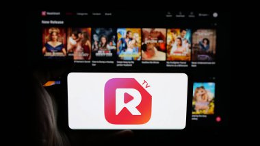 Stuttgart, Almanya - 05-31-2025: Web sayfası önünde ekranda kısa video yayınlama uygulaması şirketi ReelShort 'un logosuna sahip cep telefonu tutan kişi. Telefon ekranına odaklan.