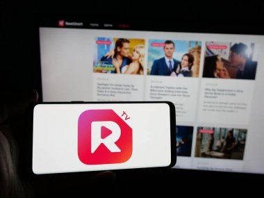 Stuttgart, Almanya - 05-31-2025: İnternet sitesinin önünde ekranda kısa video yayıncılığı uygulaması şirketi ReelShort 'un logosuna sahip akıllı telefonu tutan kişi. Telefon ekranına odaklan.