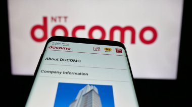 Stuttgart, Almanya - 05-31-2025: Telekomünikasyon şirketi NTT Docomo Inc. 'in web sitesiyle birlikte cep telefonu logonun önünde ekranda. Telefon ekranının sol üst kısmına odaklan.