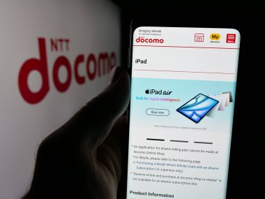 Stuttgart, Almanya - 05-31-2025: Telekomünikasyon şirketi NTT Docomo Inc. 'in web sayfası ile akıllı telefon sahibi kişi logonun önünde ekranda. Telefon ekranının merkezine odaklan.
