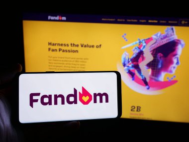 Stuttgart, Almanya - 05-31-2025: İnternet sitesi önünde ekranda Amerikan wiki hizmet şirketi Fandom Inc. 'in logosunu taşıyan kişi. Telefon ekranına odaklan.