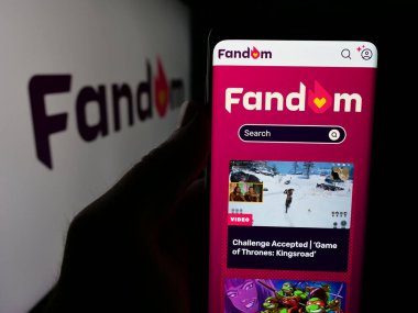 Stuttgart, Almanya - 05-31-2025: ABD wiki hizmet şirketi Fandom Inc. 'in web sayfası ile akıllı telefon sahibi kişi logo önünde ekranda. Telefon ekranının merkezine odaklan.