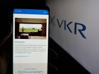 Stuttgart, Almanya - 05-31-2025: Danimarkalı yatırım şirketi VKR Holding AS 'nin web sayfası ile logo önünde cep telefonu tutan kişi. Telefon ekranının merkezine odaklan.