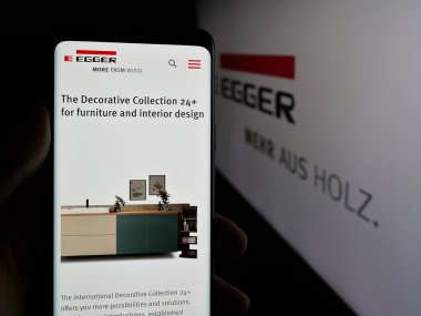 Stuttgart, Almanya - 05-31-2025: Avusturyalı Egger Holzwerkstoffe GmbH şirketinin web sayfası ile akıllı telefon sahibi kişi logonun önünde ekranda. Telefon ekranının merkezine odaklan.