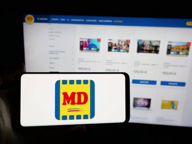 Stuttgart, Almanya - 06-01-2025: İtalyan süpermarket şirketi MD S.P.A 'nın logosunu elinde tutan kişi web sitesinin önünde ekranda. Telefon ekranına odaklan.