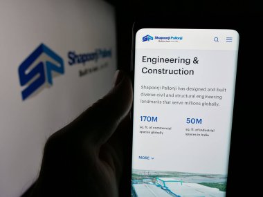 Stuttgart, Almanya - 06-01-2025: Hintli şirket Shapoorji Pallonji Group 'un web sayfası ile akıllı telefon sahibi kişi logonun önünde ekranda. Telefon ekranının merkezine odaklan.
