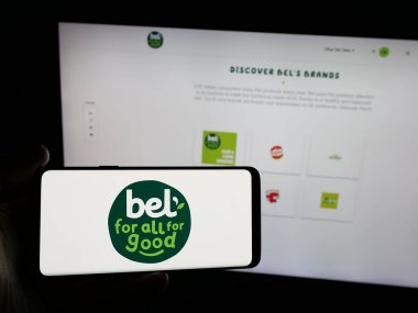 Stuttgart, Almanya - 06-02-2025: İnternet sitesinin önünde üzerinde Fransız peynir şirketi Groupe Bel 'in logosu olan akıllı telefon tutan kişi. Telefon ekranına odaklan.