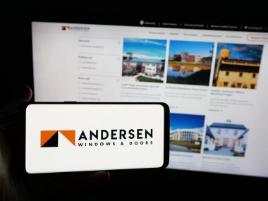 Stuttgart, Almanya - 06-04-2025: ABD 'li pencere şirketi Andersen Corporation' ın logosunun bulunduğu akıllı telefonu web sitesinin önünde tutan kişi. Telefon ekranına odaklan.