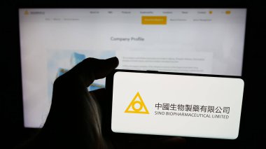 Stuttgart, Almanya - 06-04-2025: Sino Biyofarmasötik (Biopharm) logosu olan cep telefonu sahibi kişi web sayfasının önünde ekranda görülüyor. Telefon ekranına odaklan.