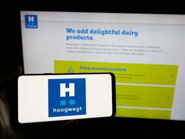 Stuttgart, Almanya - 06-04-2025: Hollandalı mandıra şirketi Hoogwegt Groep B.V. 'nin logosunu elinde tutan kişi web sitesinin önünde ekranda. Telefon ekranına odaklan.