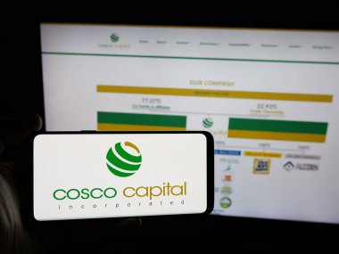 Stuttgart, Almanya - 06-04-2025: Yatırım şirketi Cosco Capital Inc. 'in logosunu elinde tutan kişi web sitesinin önünde ekranda. Telefon ekranına odaklan.