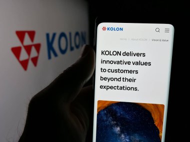 Stuttgart, Almanya - 06-04-2025: Koreli kimya şirketi Kolon Corporation 'ın web sayfası ile logo önünde cep telefonu tutan kişi. Telefon ekranının merkezine odaklan.