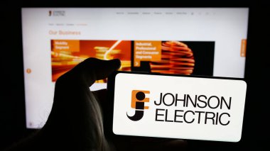 Stuttgart, Almanya - 06-04-2025: Johnson Electric Holding Limited şirketinin logosuna sahip cep telefonu sahibi kişi web sayfasının önünde ekranda. Telefon ekranına odaklan.