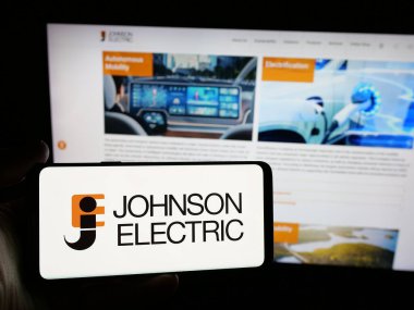 Stuttgart, Almanya - 06-04-2025: İnternet sitesi önünde ekranda Johnson Electric Holding Limited şirketinin logosuna sahip akıllı telefon sahibi kişi. Telefon ekranına odaklan.