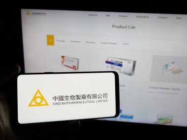 Stuttgart, Almanya - 06-04-2025: Sino Biyofarmasötik (Biopharm) logosu olan akıllı telefon sahibi kişi web sitesinin önünde ekranda görülüyor. Telefon ekranına odaklan.