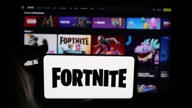 Stuttgart, Almanya - 06-05-2025: İnternet sayfası önünde Fortnite oyun platformunun logosu olan cep telefonu sahibi kişi. Telefon ekranına odaklan.
