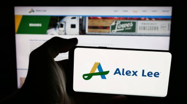 Stuttgart, Almanya - 06-05-2025: Web sayfası önünde ekranda ABD 'li toptan satış şirketi Alex Lee Inc.' in logosunu taşıyan cep telefonu sahibi. Telefon ekranına odaklan.