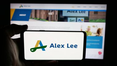 Stuttgart, Almanya - 06-05-2025: İnternet sayfası önünde ekranda ABD 'li market toptancısı Alex Lee Inc.' in logosunu taşıyan kişi. Telefon ekranına odaklan.