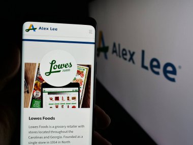 Stuttgart, Almanya - 06-05-2025: ABD 'li market toptancısı Alex Lee Inc.' in web sitesi ile akıllı telefon sahibi kişi logonun önünde ekranda. Telefon ekranının merkezine odaklan.