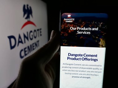 Stuttgart, Almanya - 06-05-2025: Elinde Nijeryalı malzeme şirketi Dangote Cement plc 'nin web sayfası bulunan kişi logonun önünde ekranda. Telefon ekranının merkezine odaklan.