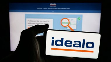 Stuttgart, Almanya - 06-05-2025: Üzerinde fiyat karşılaştırma şirketi logosu olan cep telefonu sahibi kişi idealo Internet GmbH web sayfasının önünde ekranda. Telefon ekranına odaklan.