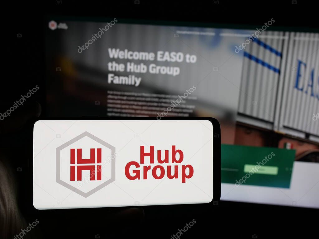 Stuttgart, Germany - 05-31-2025: Person holding smartphone with logo of US logistics company Hub Group Inc. on screen in front of website. Focus on phone display.