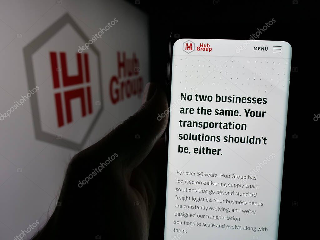 Stuttgart, Germany - 05-31-2025: Person holding smartphone with web page of US logistics company Hub Group Inc. on screen in front of logo. Focus on center of phone display.
