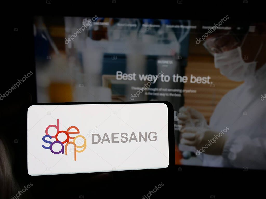 Stuttgart, Germany - 06-01-2025: Person holding smartphone with logo of Korean food company Daesang Holdings Co. Ltd. on screen in front of website. Focus on phone display.