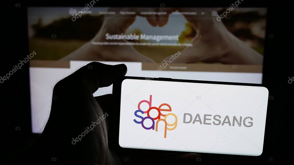 Stuttgart, Germany - 06-01-2025: Person holding mobile phone with logo of Korean food company Daesang Holdings Co. Ltd. on screen in front of web page. Focus on phone display.