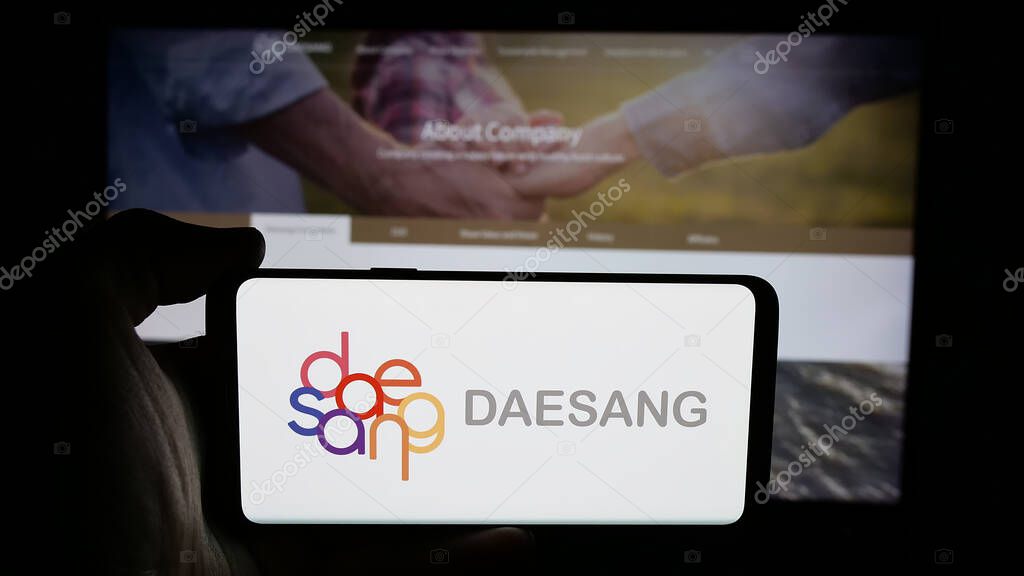 Stuttgart, Germany - 06-01-2025: Person holding cellphone with logo of Korean food company Daesang Holdings Co. Ltd. on screen in front of webpage. Focus on phone display.