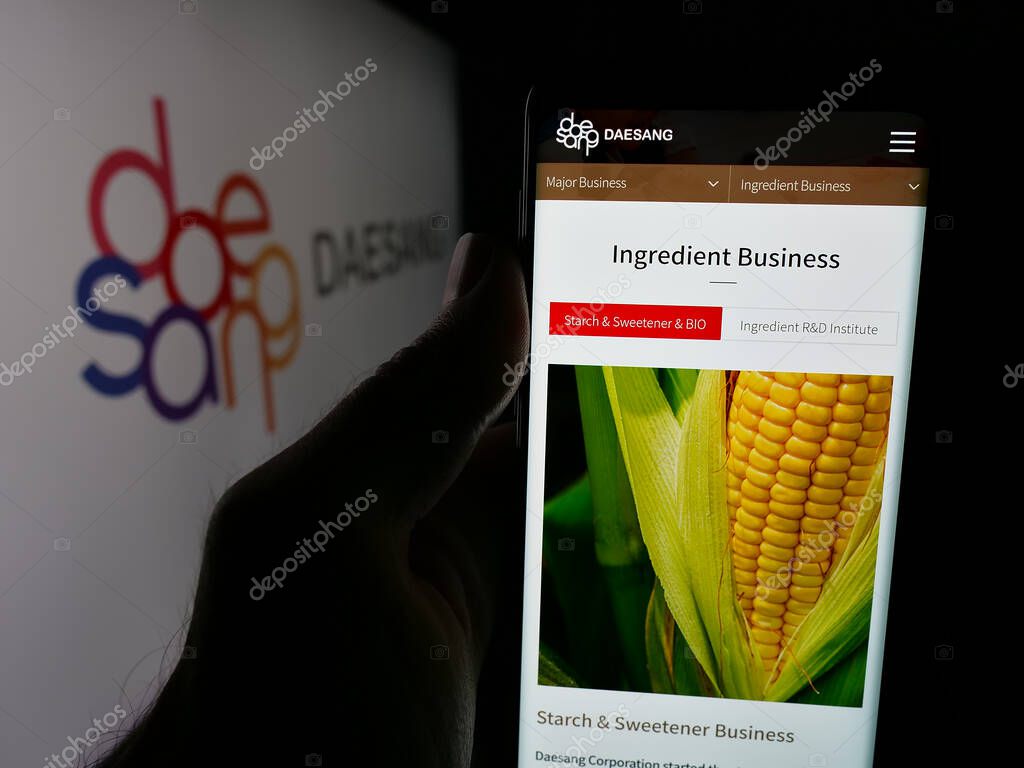 Stuttgart, Germany - 06-01-2025: Person holding smartphone with web page of Korean food company Daesang Holdings Co. Ltd. on screen in front of logo. Focus on center of phone display.