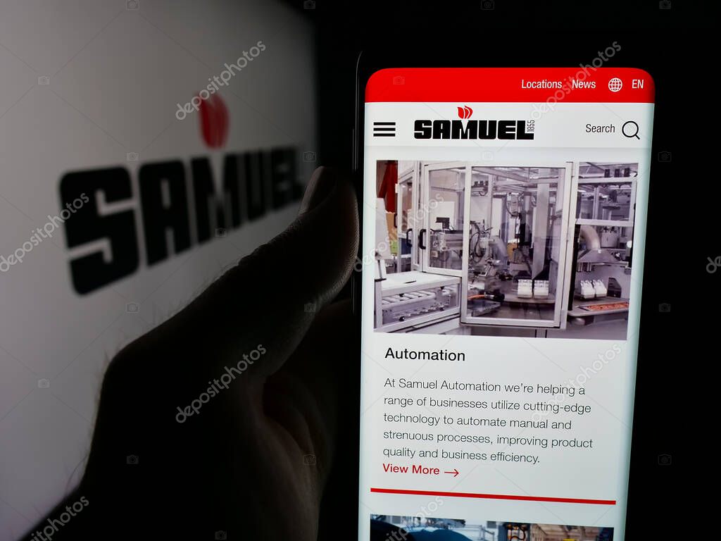 Stuttgart, Germany - 06-02-2025: Person holding smartphone with web page of metal processing company Samuel Son Co. Inc. on screen in front of logo. Focus on center of phone display.