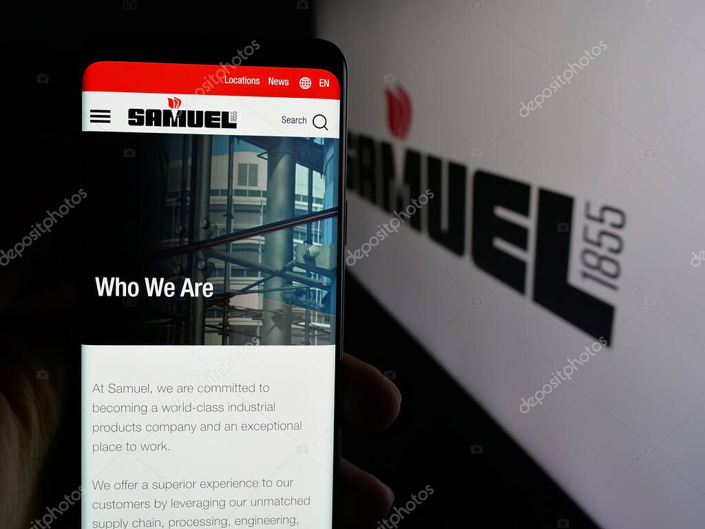 Stuttgart, Germany - 06-02-2025: Person holding cellphone with webpage of metal processing company Samuel Son Co. Inc. on screen in front of logo. Focus on center of phone display.