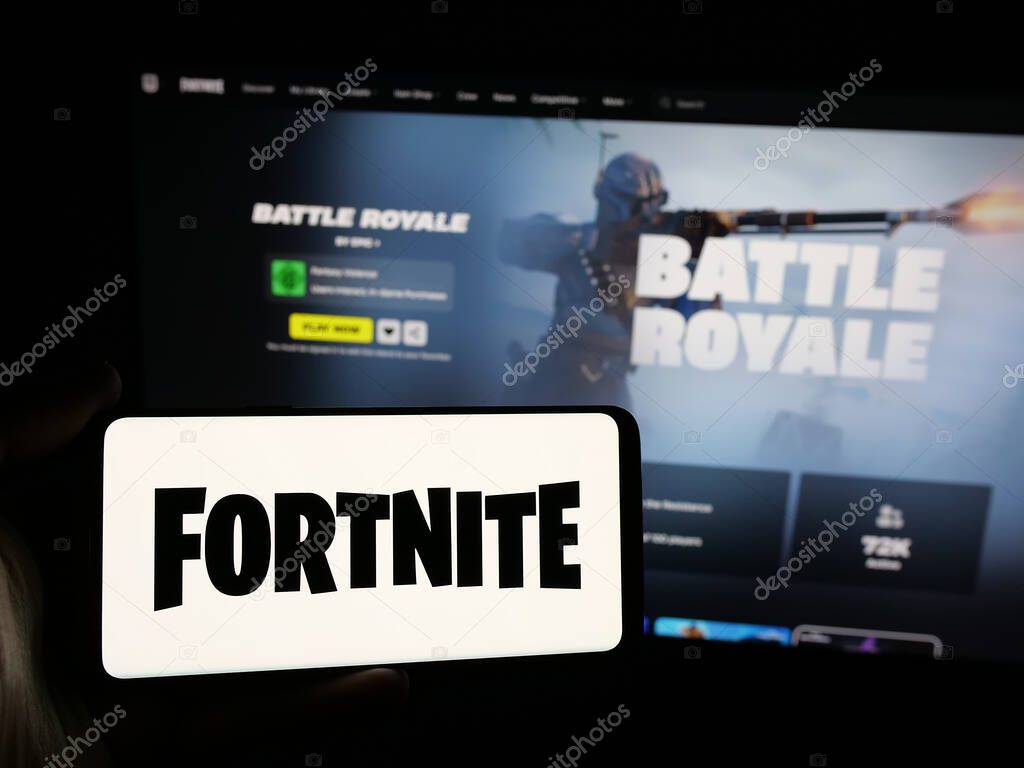 Stuttgart, Germany - 06-05-2025: Person holding smartphone with logo of online video game platform Fortnite on screen in front of website. Focus on phone display.
