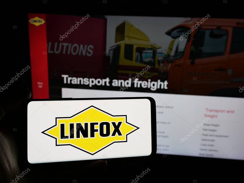 Stuttgart, Germany - 06-05-2025: Person holding smartphone with logo of Australian logistics company Linfox Pty. Ltd. on screen in front of website. Focus on phone display.