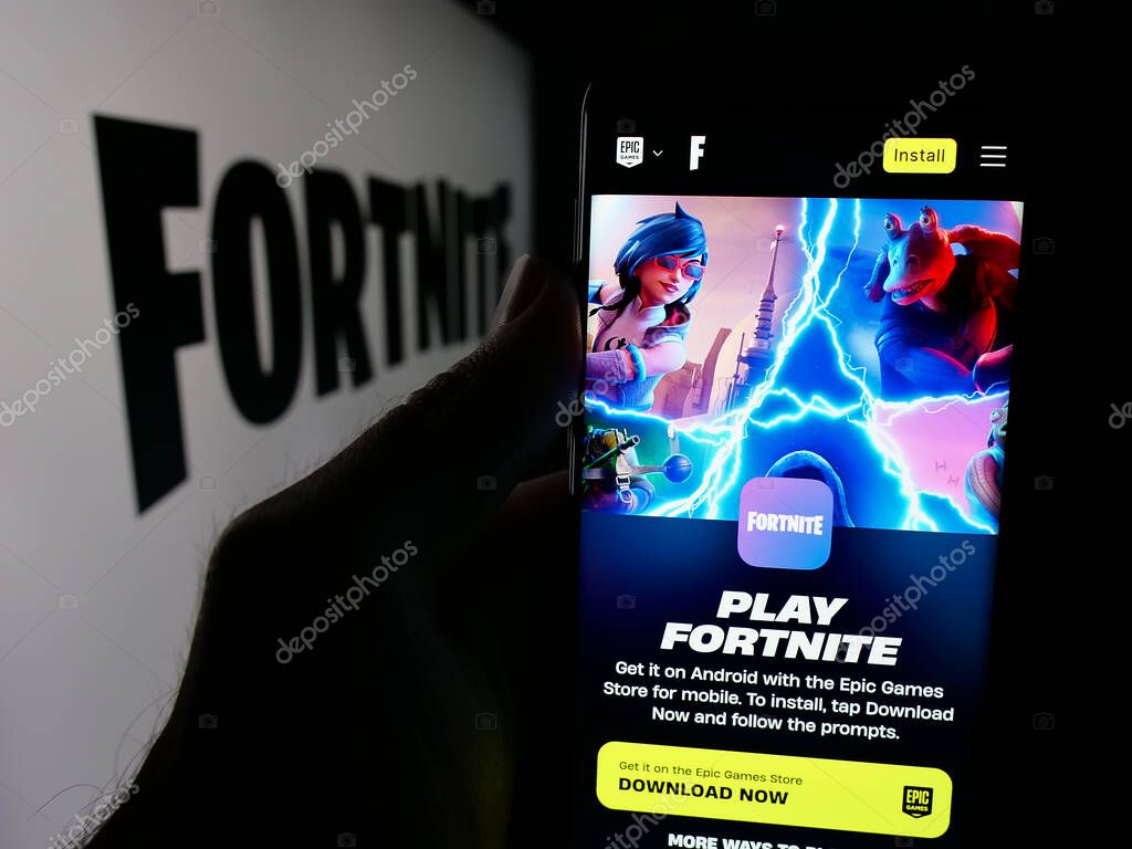 Stuttgart, Germany - 06-05-2025: Person holding smartphone with web page of online video game platform Fortnite on screen in front of logo. Focus on center of phone display.