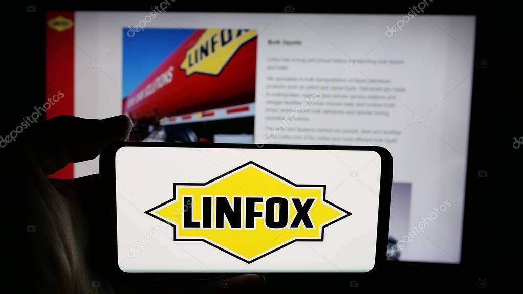 Stuttgart, Germany - 06-05-2025: Person holding cellphone with logo of Australian logistics company Linfox Pty. Ltd. on screen in front of webpage. Focus on phone display.