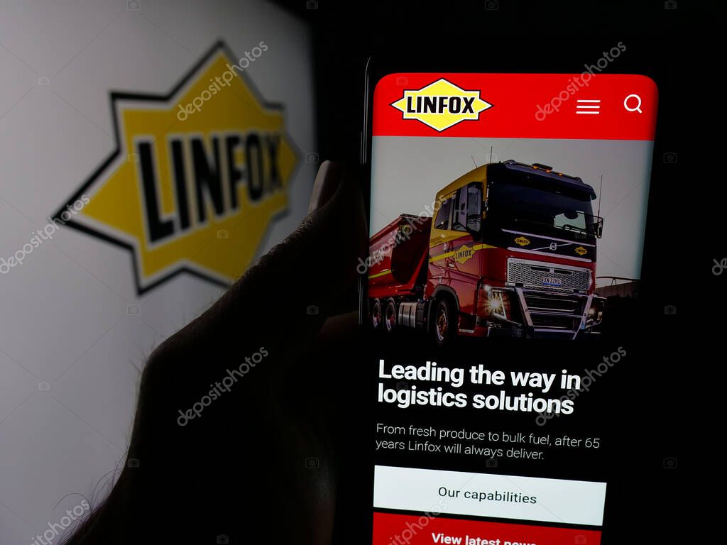 Stuttgart, Germany - 06-05-2025: Person holding cellphone with webpage of Australian logistics company Linfox Pty. Ltd. on screen in front of logo. Focus on center of phone display.