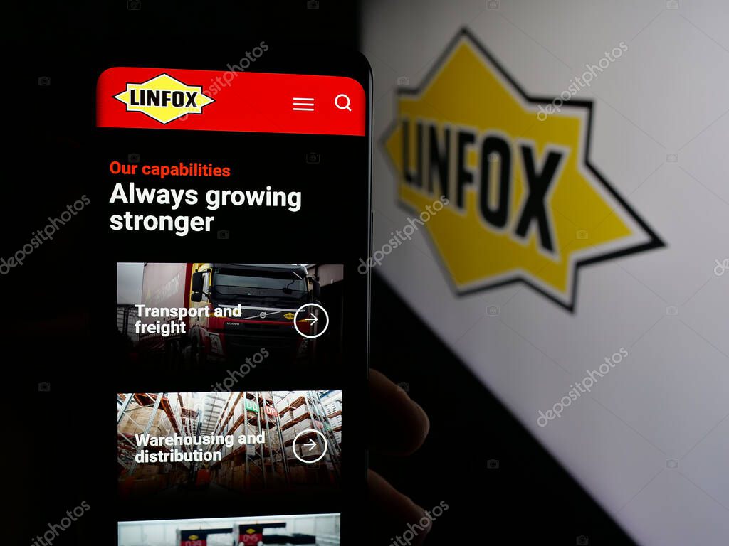 Stuttgart, Germany - 06-05-2025: Person holding smartphone with web page of Australian logistics company Linfox Pty. Ltd. on screen in front of logo. Focus on center of phone display.