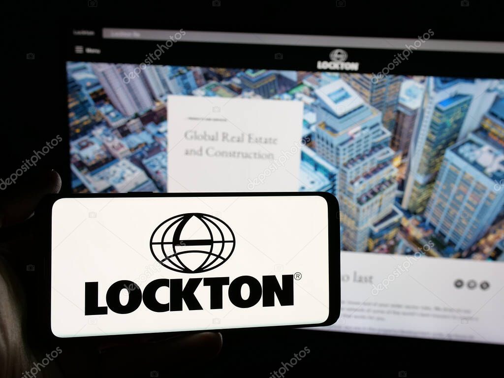 Stuttgart, Germany - 06-05-2025: Person holding smartphone with logo of financial services company Lockton Companies on screen in front of website. Focus on phone display.